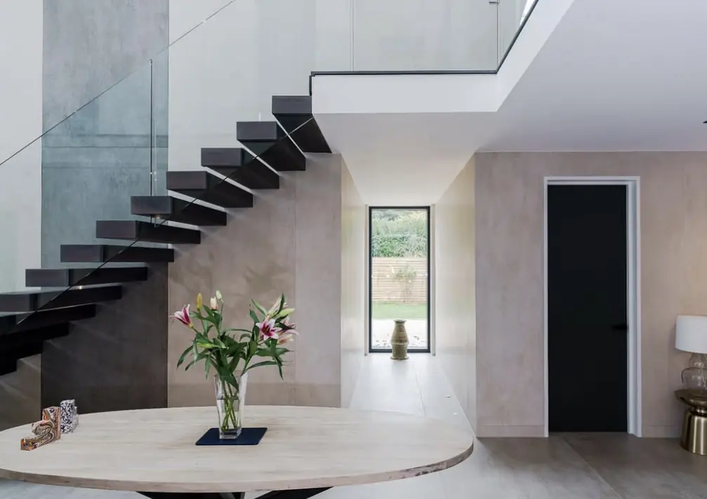 Double-height hall with a floating staircase over pale stone